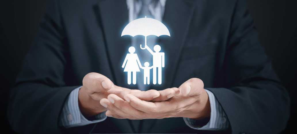 A businessperson in a suit holding an illustration of a family under an umbrella, symbolizing protection, security, and insurance.